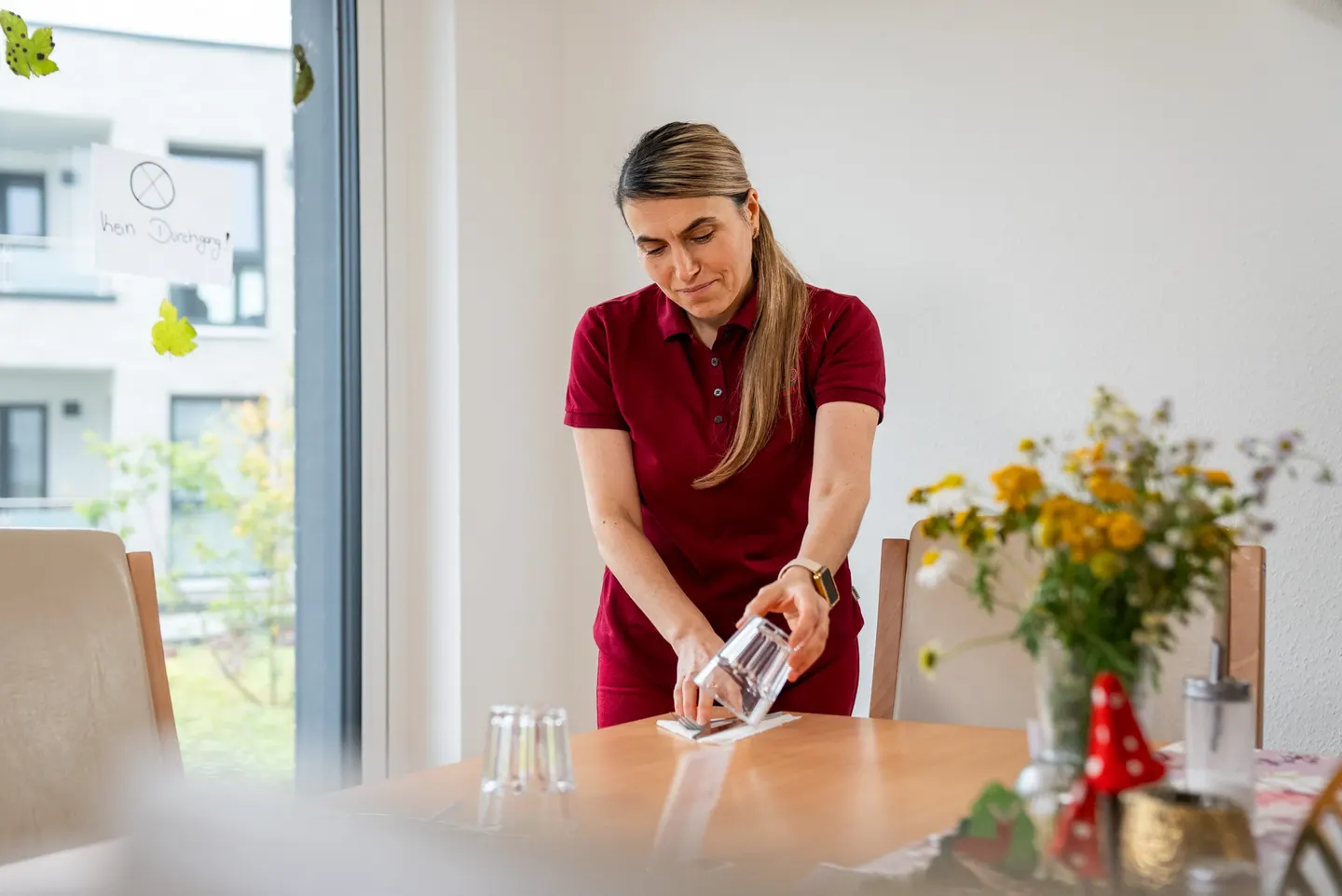 Cardia-Mitarbeiterin reinigt einen Tisch im Gemeinschaftsraum der Springbachhöfe